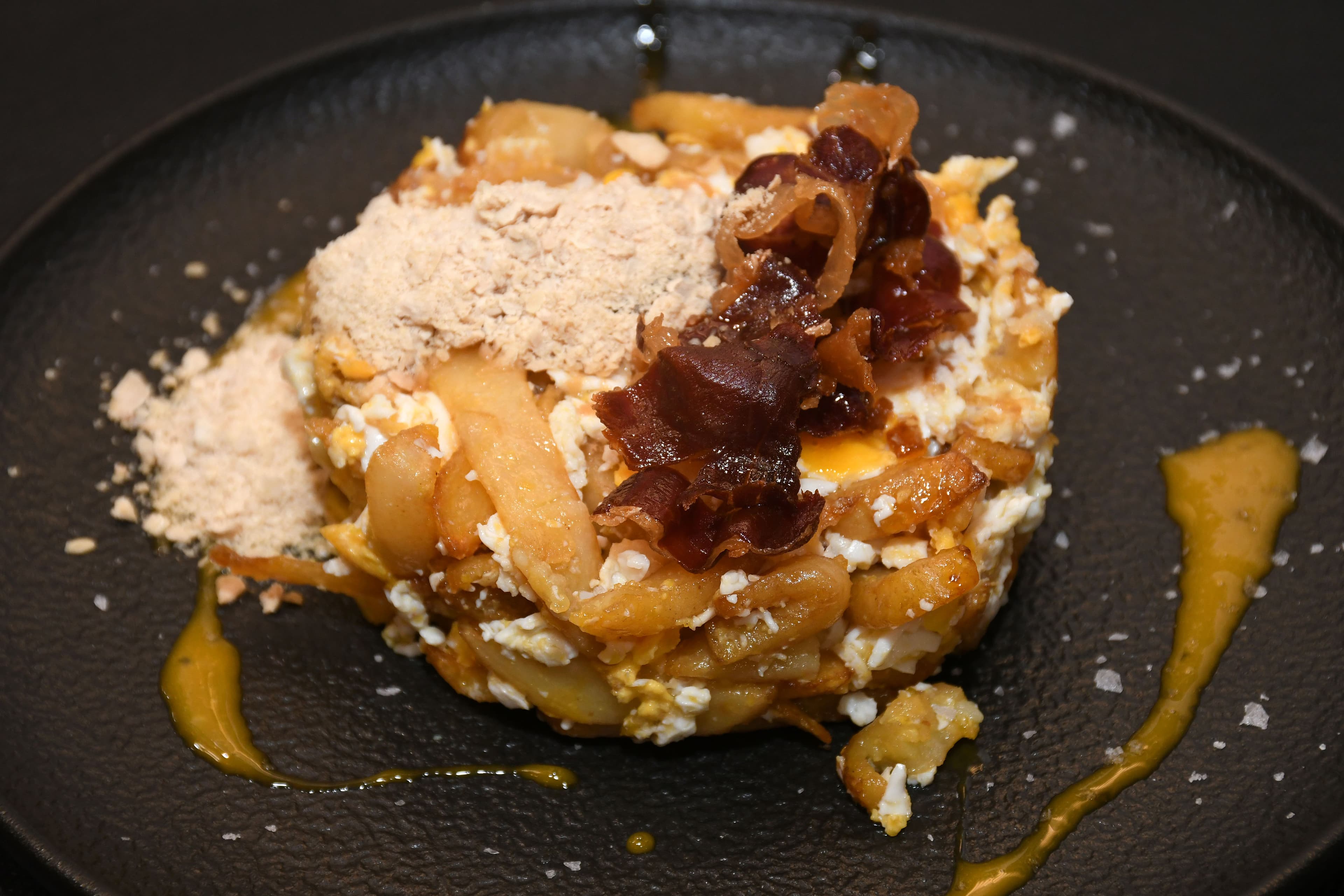 Huevos rotos con jamón ibérico y foie servidos sobre patatas