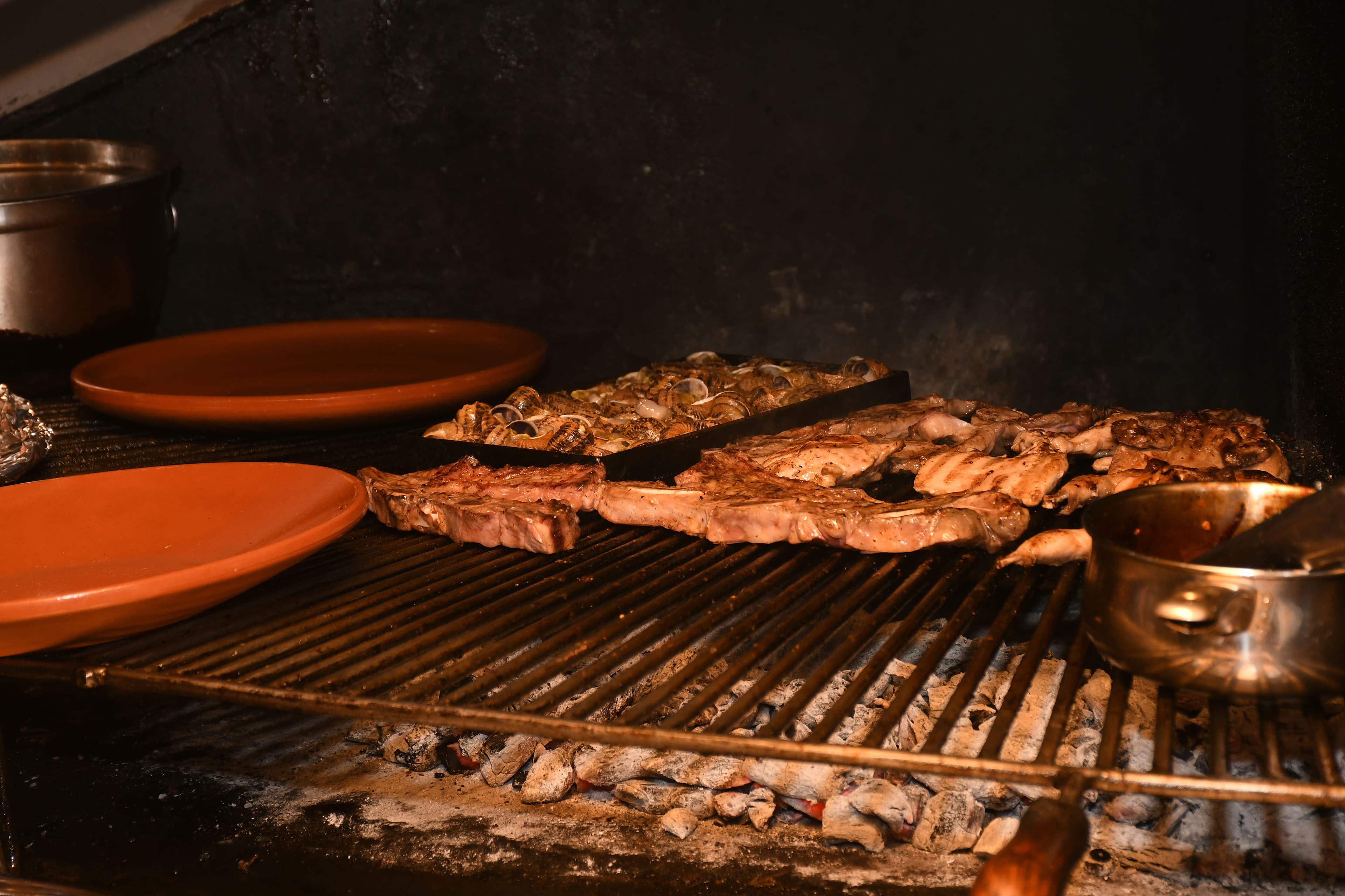 Brasas de carbón vegetal vivas en la parrilla de Brasa Los Cántaros